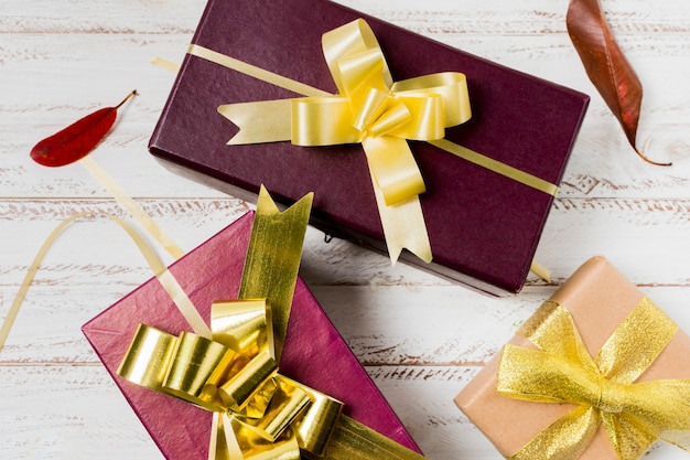 Close-up of attractive gift boxed and leaves on painted wooden plank