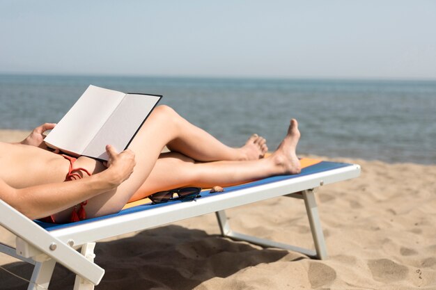 Close up back view woman on beach chair reading