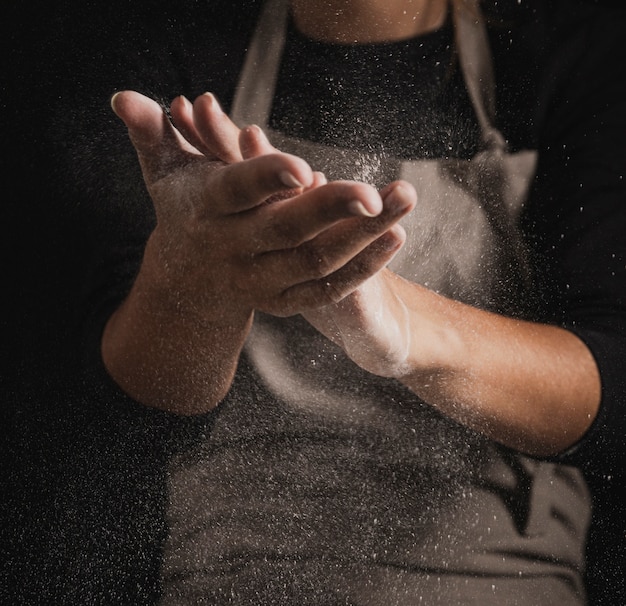 Free photo close-up baker cleaning hands off flour