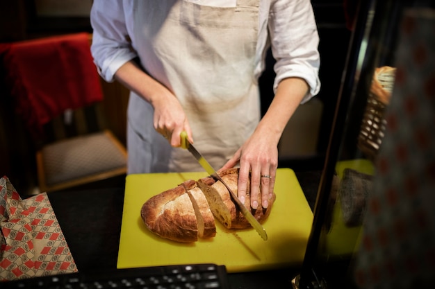 Close up baker cutting bread