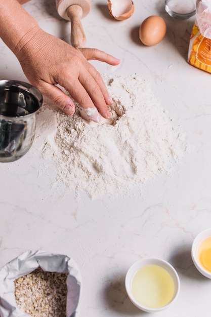 Free photo close-up of a baker's hand with various baking ingredients on kitchen counter