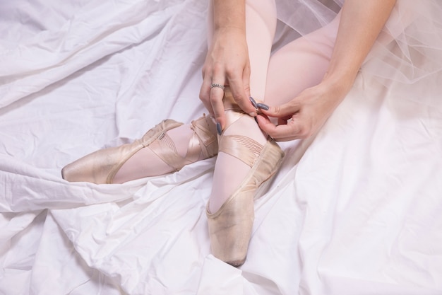 Close up ballerina tying pointe shoes