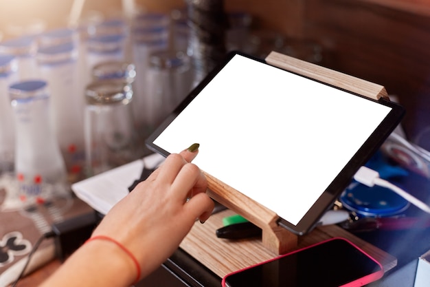 Close up of barista finger with manicure scrolling tablet pc at cafe