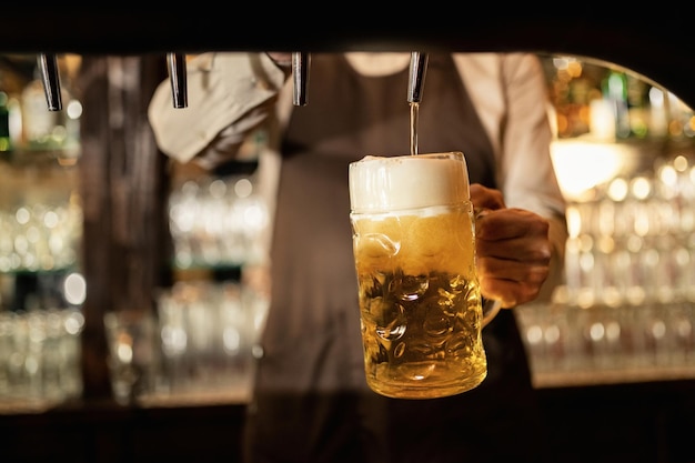 Free photo close-up of barista pouring beer from beer tap while working in a pub.