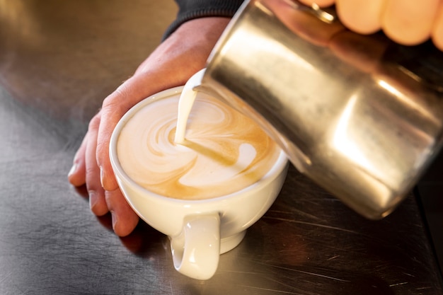 Close-up barista pouring coffee into cup