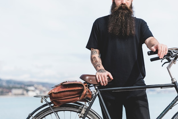 Free photo close-up of bearded young man standing with his bicycle