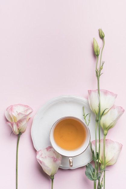 Close-up of beautiful eustoma flowers with cup of tea against pink background