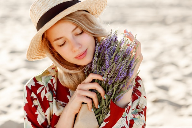 Free photo close up beauty portrait of lovely romantic blond girl  enjoying perfect smell of lavender. skincare and cosmetic concept. warm sunset colors. close eyes.