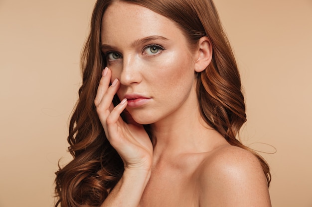 Free photo close up beauty portrait of sensual ginger woman with long hair posing with arm near face while looking