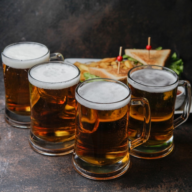 Free photo close-up beer with a plate of sandwich and fried potatoes