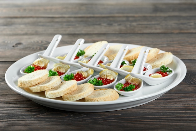 Close-up of a big plate,served for a restaurant buffet with a tasty snacks made from red caviar,white bread, lemon slices and cream. Looks very delicios and good for banquets and catering.