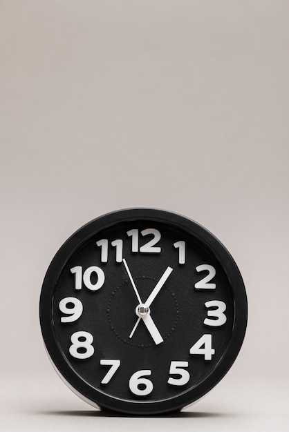 Free Photo close-up of a black alarm clock on plain background