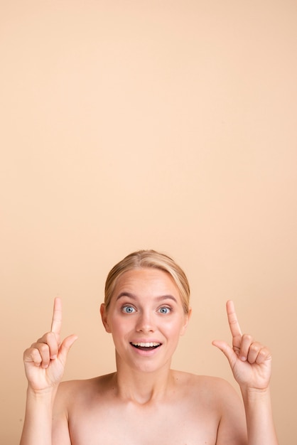 Free Photo close-up blonde smiley woman pointing up