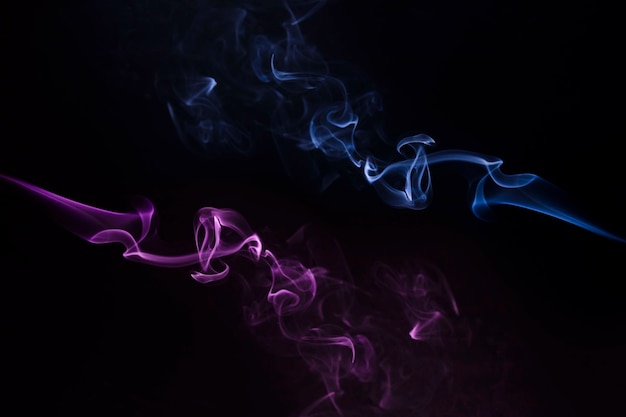 Free Photo close-up of blue and purple smoke swirling against black backdrop