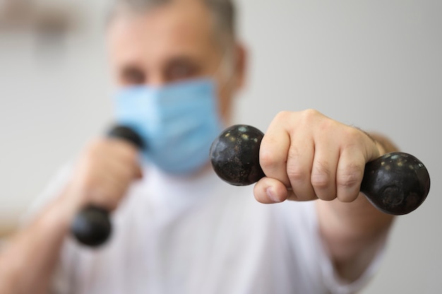 Close-up blurry man holding dumbbells