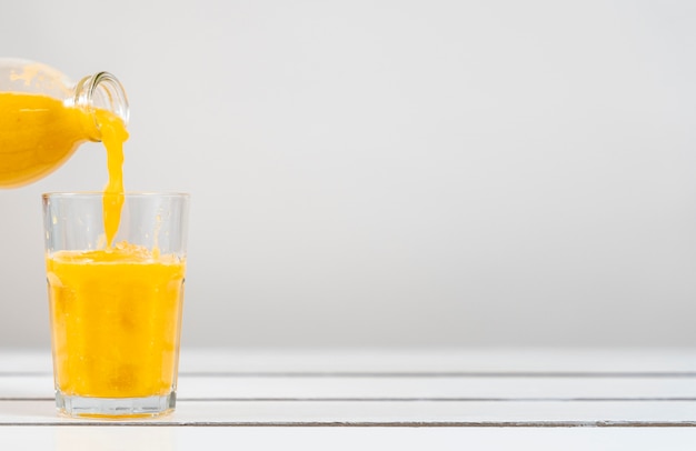 Free photo close-up bottle pouring juice in glass