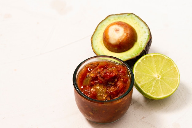 Close-up bowl of sauce near avocado and lime