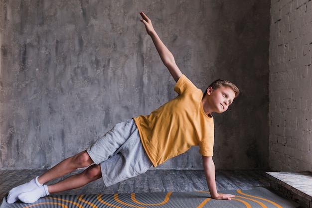 Close-up of a boy doing stretching exercising against concrete wall