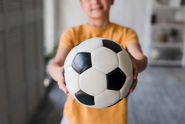 Free Photo close-up of boy giving soccer ball toward camera