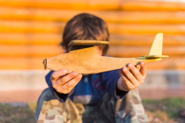 Free photo close-up of boy holding wooden aeroplane in his hands