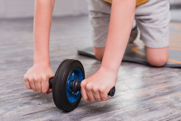 Close-up of a boy kneeling exercising with roller slide