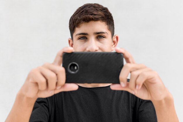 Free Photo close-up of boy taking picture through the cellphone against white background