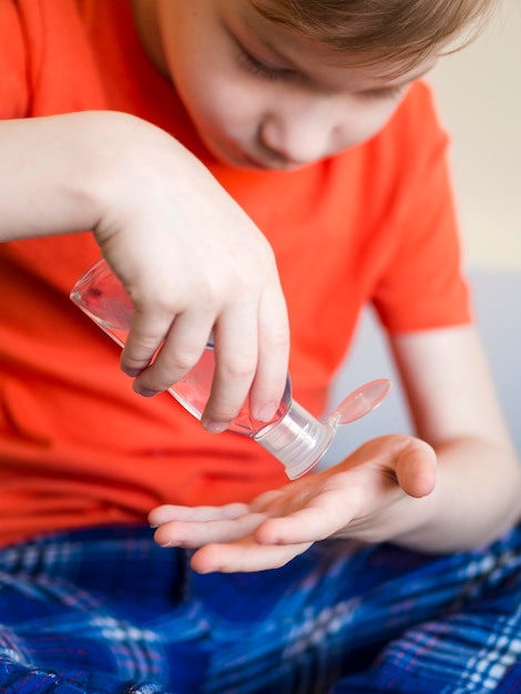 Free Photo close-up boy using hand sanitizer