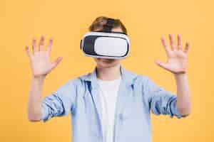 Free photo close-up of a boy using with virtual reality goggles against yellow background