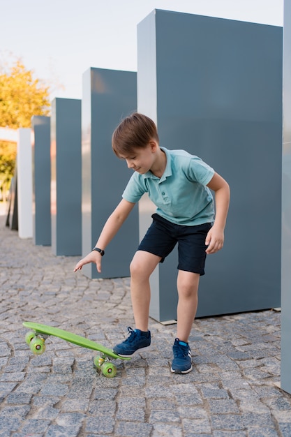 Free Photo close up boy wearing blue sneakers practicing with green skateboard. active urban lifestyle of youth, training, hobby, activity. active outdoor sport for kids. child skateboarding.