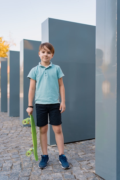 Free photo close up boy wearing blue sneakers practicing with green skateboard. active urban lifestyle of youth, training, hobby, activity. active outdoor sport for kids. child skateboarding.