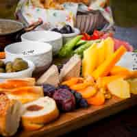 Free photo close-up breakfast different types of cheese, cucumbers, tomatoes, lettuce, dried apricots, raisins, dates on a wooden stand