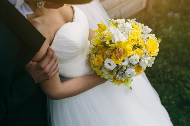 Close-up of bride holding a bouquet of roses