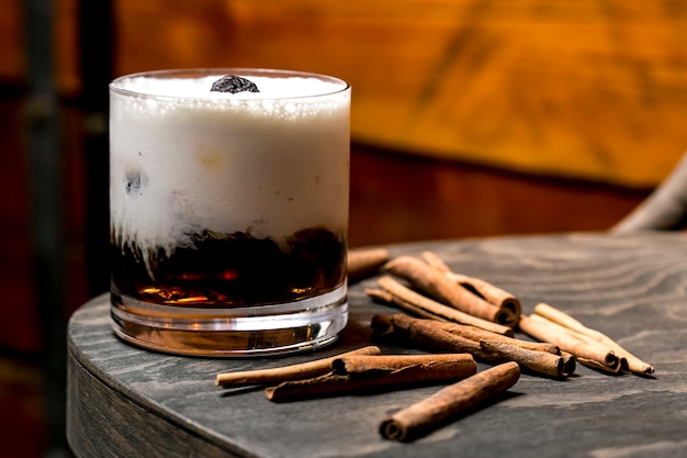 Free Photo close up of a brown creamy cocktail glass next to cinnamon sticks