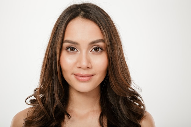 Close up brunette woman looking at the camera over gray