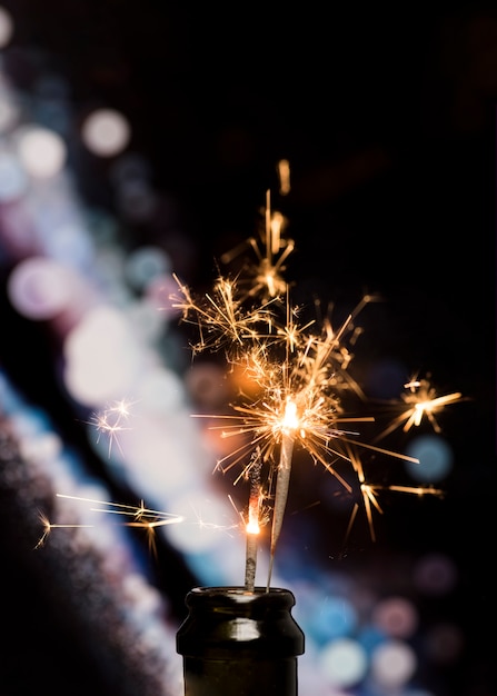 Free Photo close-up of burning sparkler in bottle on bokeh background