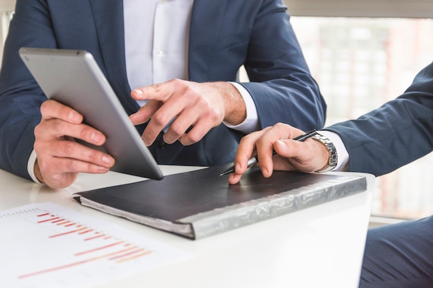 Close-up of businessman discussing financial report on digital tablet