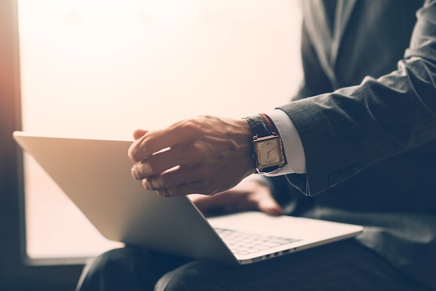 Close-up of a businessman holding laptop on his lap