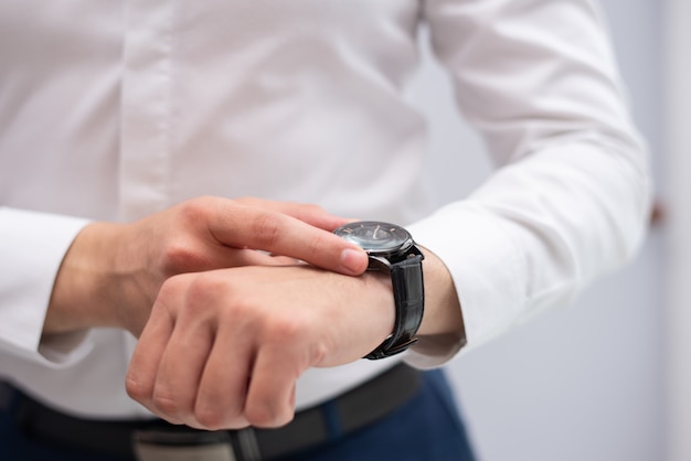 Close-up of businessman looking at his modern wristwatch