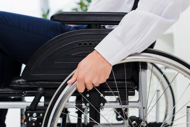 Close-up of a businessman's hand on wheel of wheelchair