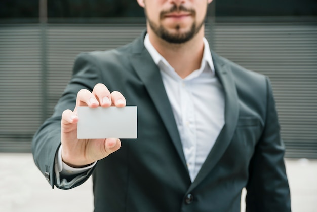 Free Photo close-up of a businessman standing at outdoors showing blank white business card