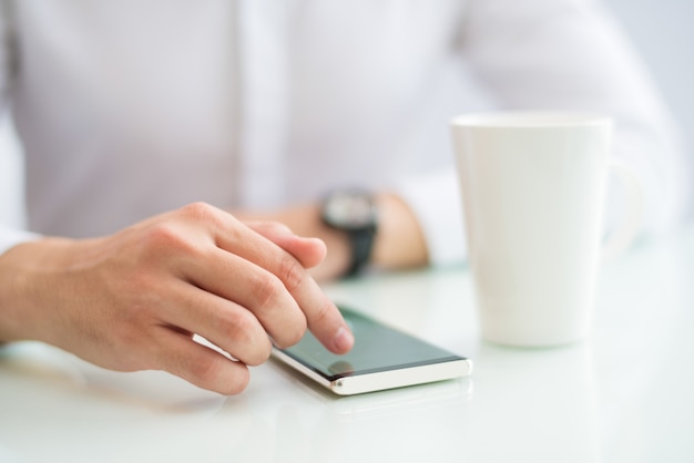 Close-up of businessman touching screen of smartphone