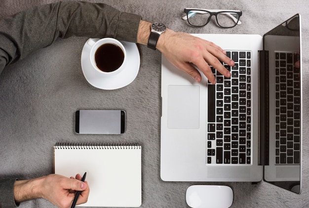 Free photo close-up of a businessman writing on clipboard using digital tablet on desk