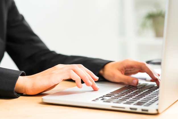 Free Photo close-up of businesswoman's hand typing on laptop over desk