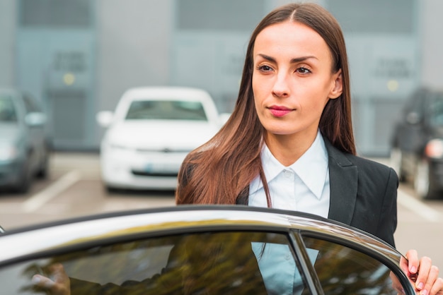 Free photo close-up of a businesswoman standing behind the car door