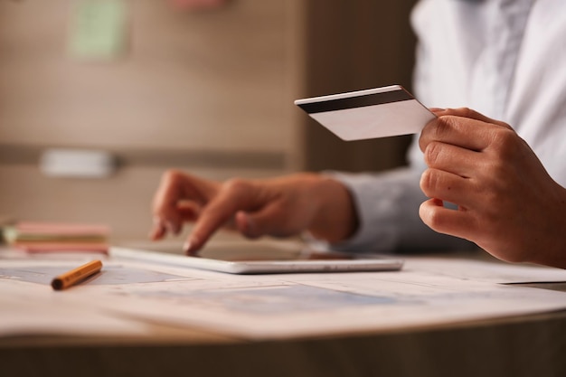 Close up of businesswoman with credit card checking her bank account on digital tablet