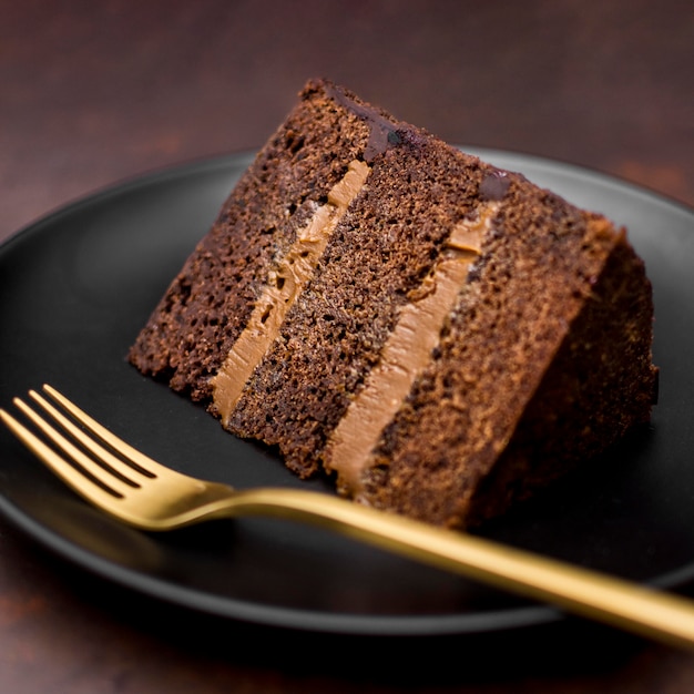 Free photo close-up of cake slice on plate with golden fork