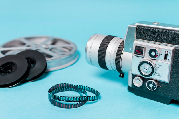 Free Photo close-up of camcorder with film reels and filmstrips on blue backdrop