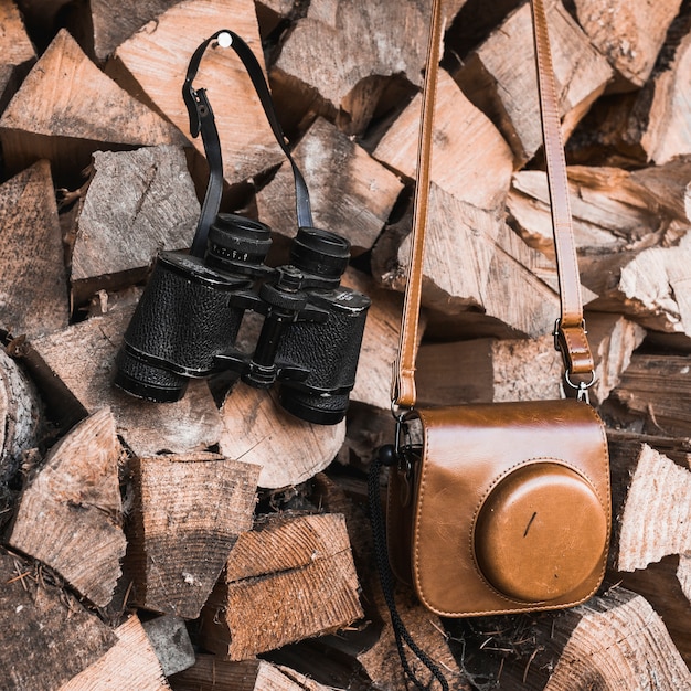 Free photo close-up camera and binoculars on firewood