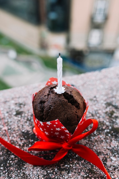 Free photo close-up of candle on cake decorated with red ribbon