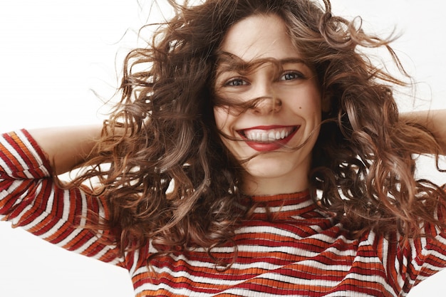 Close-up of carefree attractive woman with curly hair smiling